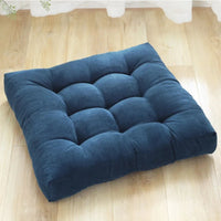 Coussin capitonné carré bleu posé sur le parquet