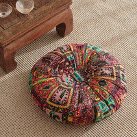 coussin de méditation style bohème rouge capitoné au centre il est posé sur le un sol tissé en haut q gauche de l'image une table basse en bois