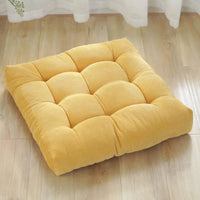 Coussin capitonné carré jaune posé sur le parquet