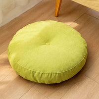 Coussin de sol rond vert en tissu, posé sur un sol en bois clair, apportant fraîcheur et confort à votre intérieur.