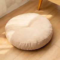 Coussin de sol rond beige en tissu, posé sur un sol en bois clair, apportant douceur et confort à votre intérieur.