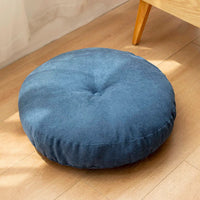 Coussin de sol rond bleu en tissu, posé sur un sol en bois clair, apportant confort et style à votre intérieur.