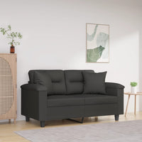 Canapé noir élégant à deux places dans un salon minimaliste, décoré avec une armoire en bois, une table basse et un tableau mural abstrait.