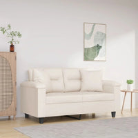 Canapé crème moderne à deux places dans un salon minimaliste, décoré avec une armoire en bois, une table basse et un tableau mural abstrait.