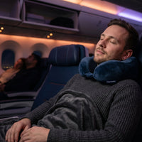 une personne qui dort dans l'avion avec un coussin ergonomique 