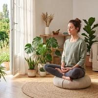 Un gros plan photoréaliste de haute qualité sur une femme sereine méditant en position du lotus sur un coussin de méditation zafu rond dans un salon minimaliste baigné de lumière naturelle matinale à Pullay