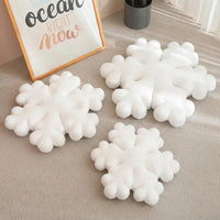 Coussin de Noël en forme de flocon blanc moelleux sur tapis beige, décoration hivernale cocooning