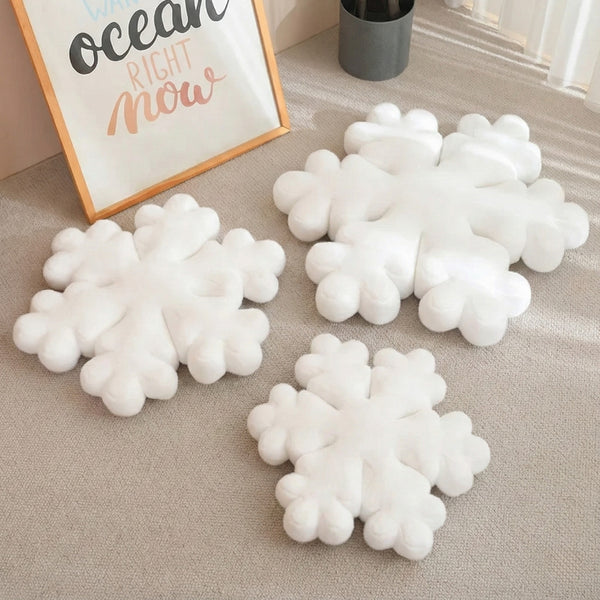 Coussin de Noël en forme de flocon blanc moelleux sur tapis beige, décoration hivernale cocooning