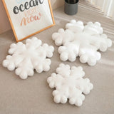 Coussin de Noël en forme de flocon blanc moelleux sur tapis beige, décoration hivernale cocooning