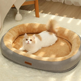 coussin pour chat en forme de ovale avec des bord surélevé beige à l'intérieur et gris à l'exterieur un chat est allongé dedans posé sur un tapis molletoné