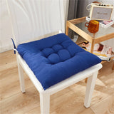 Coussin de chaise bleu sur une chaise blanche en bois, posé dans un intérieur moderne avec un sol en bois clair.