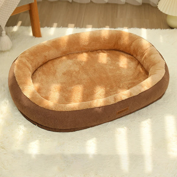 coussin pour chat en forme de ovale avec des bord surélevé beige à l'intérieur et marron à l'exterieur posé sur un tapis molletoné