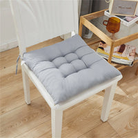 Coussin de chaise gris sur une chaise blanche en bois, posé dans un intérieur moderne avec un sol en bois clair.