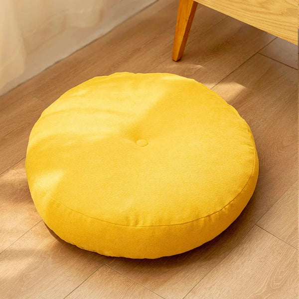 Coussin de sol rond jaune en tissu, posé sur un sol en bois clair, apportant couleur et confort à votre intérieur.