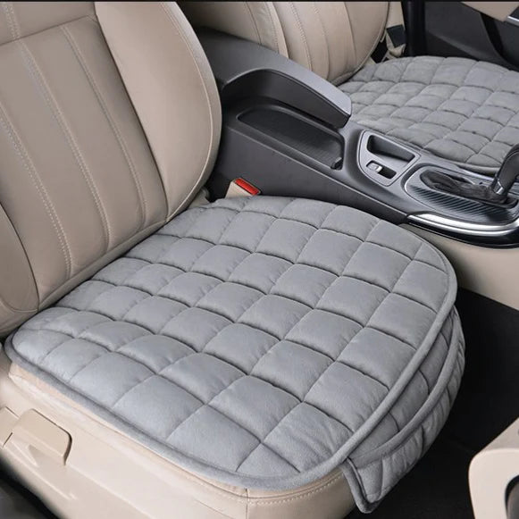 Coussin de voiture pour assise de siège avec poche gris installé sur les deux sièges avant beige d'une voiture 