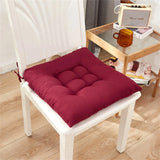 Coussin de chaise bordeaux sur une chaise blanche en bois, placé dans un intérieur moderne avec un sol en bois clair.