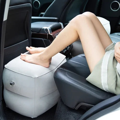 Coussin gonflable et ajustable de voyage installé sur le sol d'une voiture a l'arrière avec une personne posant ses pieds dessus